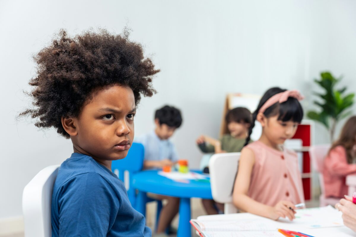 A young boy in class, frowning